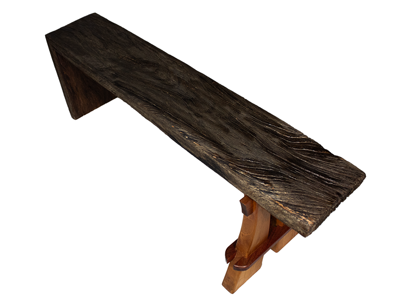 Weathered mahogany waterfall bench with sculpted split leg and purple heart accents. Top view.