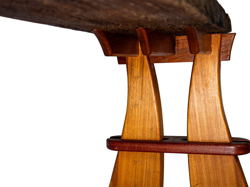 Weathered mahogany waterfall bench with sculpted split leg and purple heart accents. Attachment points.