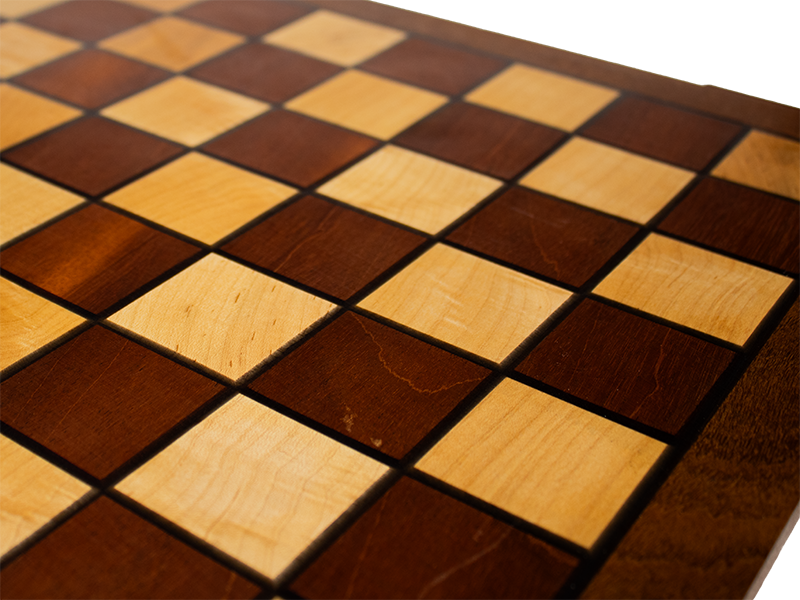 Chessboard made from Mahogany and Hard Maple with an Ipe border and Spanish Cedar feet and black resin lines, close up top view.